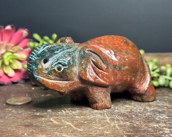 May include: A hand-carved red, green, and brown jasper elephant figurine. The elephant is standing on all four legs with its trunk raised.