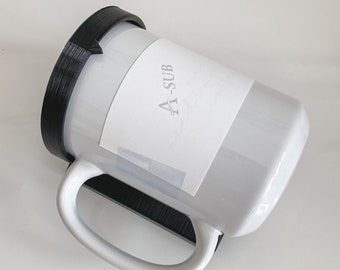 May include: White ceramic mug with a black lid and a black handle. The mug has a white label with the text "A-SUB" printed on it.