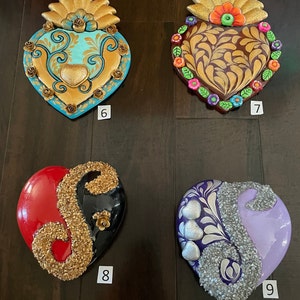 May include: Four handmade heart-shaped ornaments with different designs and colors. The ornaments are decorated with gold, silver, and glitter. The ornaments are numbered 6, 7, 8, and 9.
