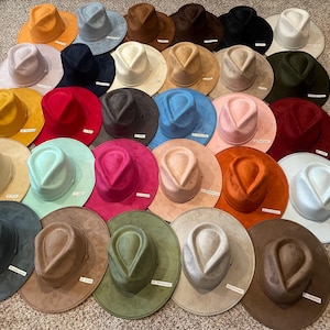 May include: A collection of 25 wide-brimmed felt hats in various colours, including brown, blue, pink, red, and green. The hats have a unique, indented crown shape.