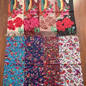 May include: Eight rectangular scarves with fringe ends. The top row features four scarves depicting the Virgin of Guadalupe with roses in cream, maroon, tan, and black. The bottom row features four scarves with colorful floral and bird patterns.