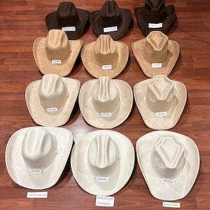 Puede incluir: Una colección de doce sombreros de vaquero dispuestos en cuatro filas de tres, con cuatro variaciones de color distintas: chocolate, camello, beige y perla. Cada sombrero muestra una pequeña etiqueta blanca que indica su color, con etiquetas adicionales que dicen CHIHUAHUA, AMERICAN COWBOY y WESTERN.