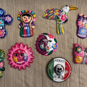 Mexican Ceramic I. Mexican ceramic magnets, charro hats, and metal figures. All with traditional designs.