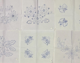 May include: A set of white fabric squares featuring blue ink embroidery patterns of poinsettias, holly, bells, and fruit. Each square is numbered from 10 to 15, displaying detailed line art designs for needlework projects on a plain background.