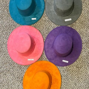 May include: Five colorful hats in aqua, gray, pink, purple, and orange are displayed. Each hat has a wide brim and a cylindrical crown. The hats are labeled with color names and numbers: 20 Aqua, 42 Elephant, 18 Rosella, 36 Purple, and 44 Orange.