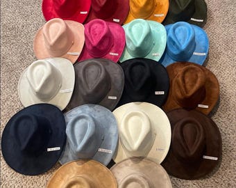 Könnte beinhalten: Eine Sammlung von 18 Fedoras aus Wildleder in verschiedenen Farben, darunter Schwarz, Weiß, Braun, Blau, Rot, Grün und Gelb. Jeder Hut hat ein Etikett mit einem Farbnamen.