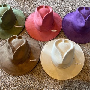 K&ouml;nnte beinhalten: Sechs H&uuml;te aus Wildleder in verschiedenen Farben, darunter Gr&uuml;n, Pink, Lila, Braun und Beige. Jeder Hut hat eine herzf&ouml;rmige Krone und eine breite Krempe.