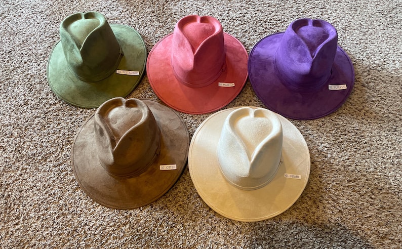 K&ouml;nnte beinhalten: Sechs H&uuml;te aus Wildleder in verschiedenen Farben, darunter Gr&uuml;n, Pink, Lila, Braun und Beige. Jeder Hut hat eine herzf&ouml;rmige Krone und eine breite Krempe.