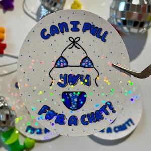 May include: A round, white sticker with the text "Can I pull you for a chat?" in blue. The sticker features a blue bikini graphic with star patterns. The background has a glittery effect.