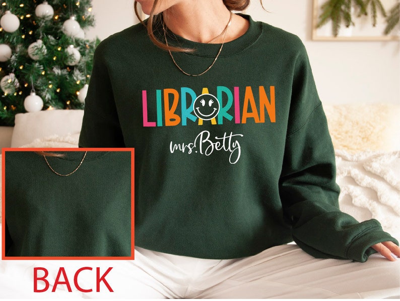 May include: Green sweatshirt with the text "LIBRARIAN mrs. Betty" in colorful letters with a smiley face in the middle of the word "LIBRARIAN".