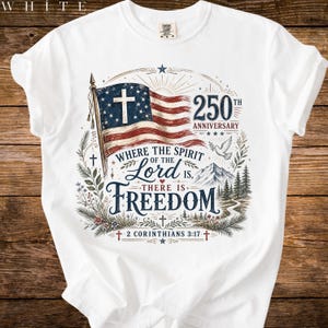 Könnte beinhalten: Ein weißes T-Shirt mit einer Grafik einer amerikanischen Flagge mit einem Kreuz im blauen Feld. Der Text lautet 250th Anniversary, Where the Spirit of the Lord is, there is Freedom und 2 Corinthians 3:17, ergänzt durch eine Taube und Berg.
