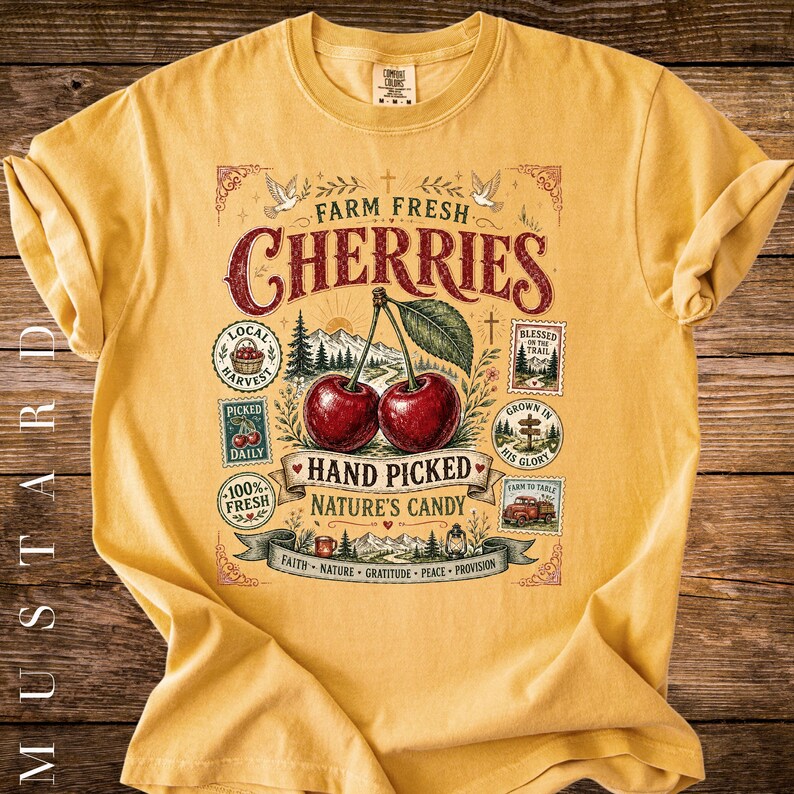 May include: Mustard-colored t-shirt featuring a vintage-style graphic with the words "Farm Fresh Cherries." The design includes two cherries, text, and decorative elements. The shirt is made of a soft material.