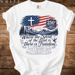 Könnte beinhalten: Ein weißes T-Shirt mit einer Grafik aus amerikanischer Flagge, Kreuz, Bergen und einer Taube. Der Text lautet: Where the Spirit of the Lord is, there is Freedom, 2 Corinthians 3:17, 250th Anniversary 1776-2026, Faith, Freedom, Grace, Independence Day 2026.