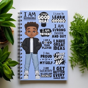 Peut inclure: Un carnet &agrave; spirales bleu avec une illustration de dessin anim&eacute; d'un jeune gar&ccedil;on noir portant une veste noire, un jean bleu et des baskets blanches. Le carnet est recouvert d'affirmations positives en texte noir, telles que "Je suis responsable", "J'ai de bonnes id&eacute;es", "Je suis patient", "Je suis un bon joueur d'&eacute;quipe", "Je suis fier de moi", "Je suis digne d'amour et de respect", "Je m'am&eacute;liore chaque jour".