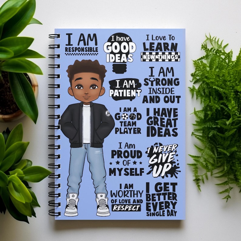 Peut inclure: Un carnet &agrave; spirales bleu avec une illustration de dessin anim&eacute; d'un jeune gar&ccedil;on noir portant une veste noire, un jean bleu et des baskets blanches. Le carnet est recouvert d'affirmations positives en texte noir, telles que "Je suis responsable", "J'ai de bonnes id&eacute;es", "Je suis patient", "Je suis un bon joueur d'&eacute;quipe", "Je suis fier de moi", "Je suis digne d'amour et de respect", "Je m'am&eacute;liore chaque jour".