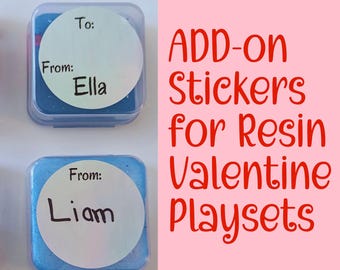 May include: Four small, square containers with blue contents and clear lids. Each has a white circle label with "To:" and "From:" written on it. One label says "From: Ella" and another says "From: Liam". Text on the right reads "ADD-ON Stickers for Resin Valentine Playsets."