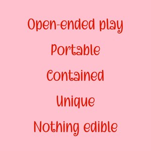 May include: A light pink background with red text. The text reads "Open-ended play, Portable, Contained, Unique, Nothing edible."