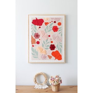 May include: A framed wall art piece with a textured, floral design. The artwork features a variety of flowers and leaves in shades of red, orange, pink, and green. The background is a light beige color.