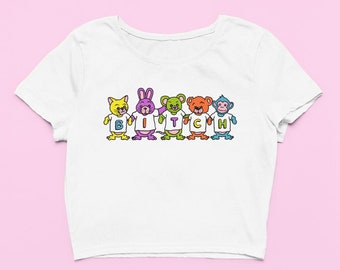 May include: White cropped t-shirt with a graphic of five cartoon animals wearing shirts that spell out "BITCH".