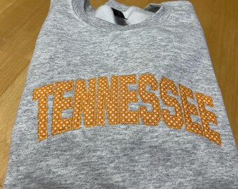 May include: A gray sweatshirt with the word "TENNESSEE" embroidered in orange with white polka dots.