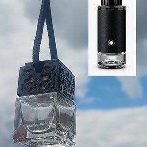May include: A black car air freshener with a square glass bottle and a black lattice design on the top. The air freshener is hanging from a black string with a silver bead.