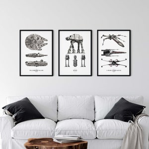 May include: Three black framed prints of Star Wars vehicles. The left print shows the Millennium Falcon, the middle print shows an AT-AT, and the right print shows an X-Wing Starfighter.