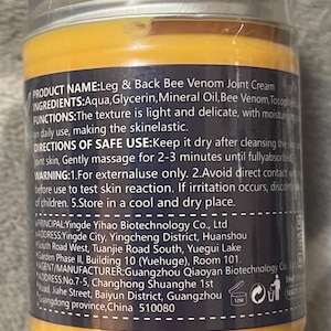 Puede incluir: Un frasco de crema para articulaciones Leg & Back Bee Venom con una etiqueta amarilla y azul marino. La etiqueta incluye informaci&oacute;n del producto, ingredientes e instrucciones de uso. El frasco tiene una tapa plateada y est&aacute; sellado.