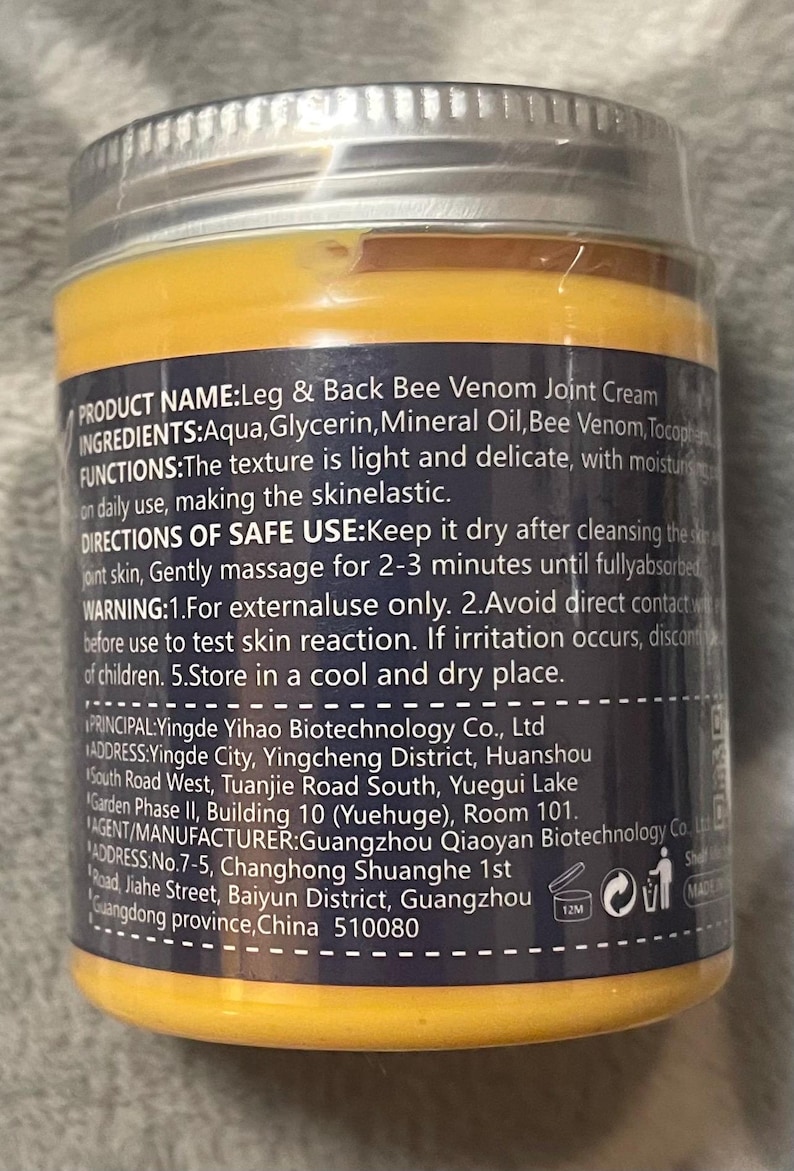 Puede incluir: Un frasco de crema para articulaciones Leg & Back Bee Venom con una etiqueta amarilla y azul marino. La etiqueta incluye informaci&oacute;n del producto, ingredientes e instrucciones de uso. El frasco tiene una tapa plateada y est&aacute; sellado.
