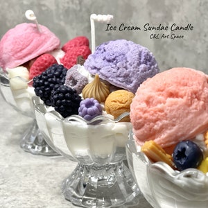 May include: Three glass sundae dishes filled with colorful ice cream, fruit, and toppings. The ice cream is pink, purple, and white. The toppings include strawberries, blueberries, blackberries, and chocolate. The text on the image reads "Ice Cream Sundae Candle C&L Art Space".