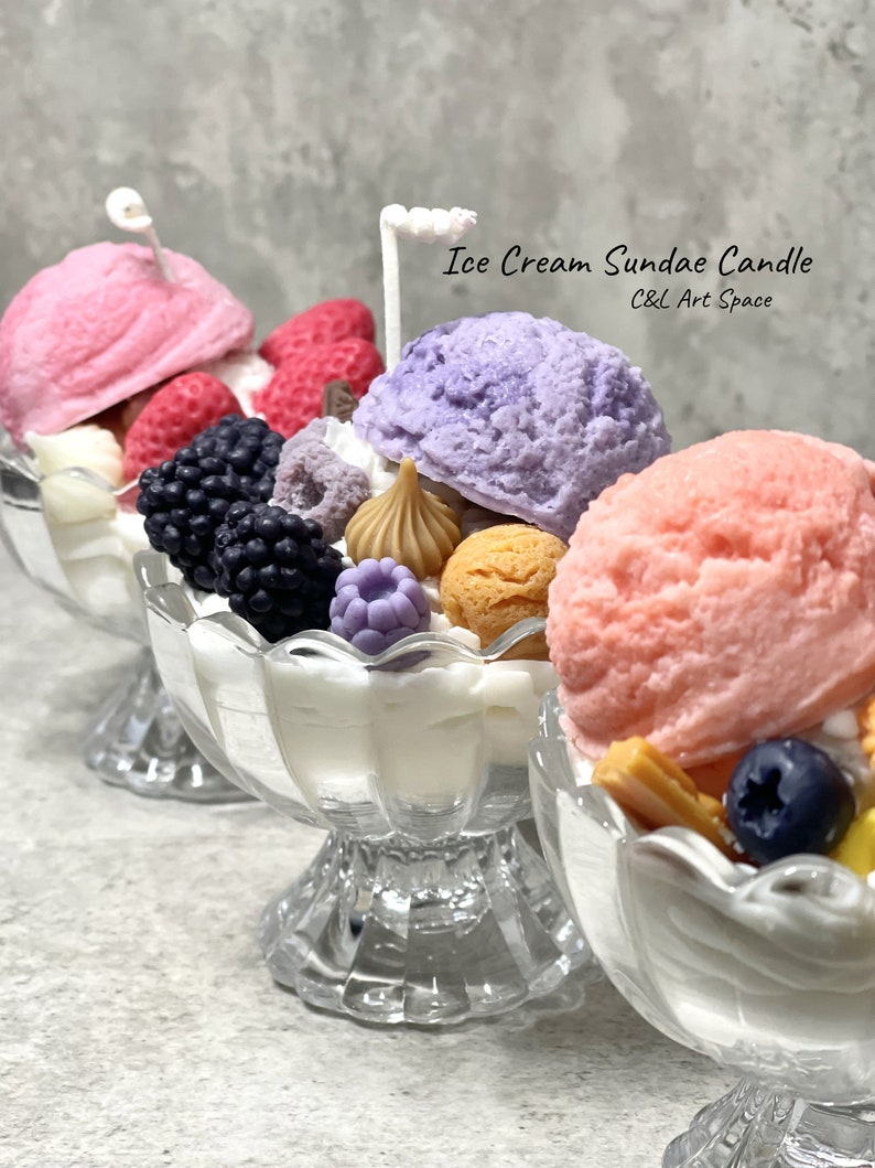 May include: Three glass sundae dishes filled with colorful ice cream, fruit, and toppings. The ice cream is pink, purple, and white. The toppings include strawberries, blueberries, blackberries, and chocolate. The text on the image reads "Ice Cream Sundae Candle C&L Art Space".