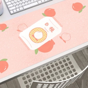 Puede incluir: Una alfombrilla de escritorio rosa con una lata blanca de zumo de melocotón e ilustraciones de melocotones. La lata tiene el texto "Melocotón" en caracteres chinos y "Familia" en inglés.