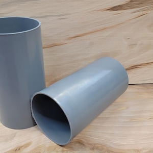 May include: Two gray plastic cylinders, one standing upright and the other lying on its side.