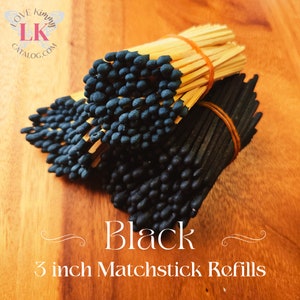 May include: A bundle of black matchstick refills, 3 inches long, tied together with rubber bands. The matchsticks are arranged in a stack, with the black tips facing out. The matchsticks are on a wooden surface.