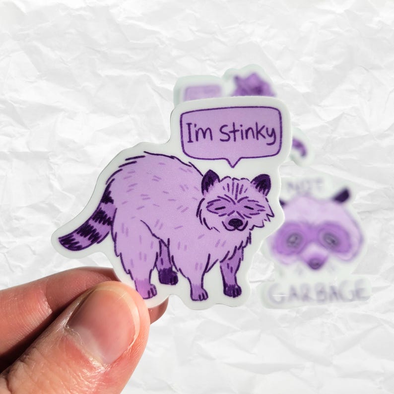以下が含まれることがあります： 紫色のアライグマのステッカーで、吹き出しの中に「I'm Stinky」という文字が書かれています。アライグマは四つん這いで立っており、かわいい表情をしています。