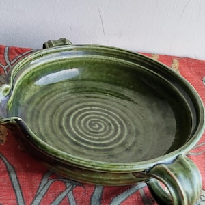 May include: A green ceramic serving bowl with two handles. The bowl has a spiral design and a glossy finish.