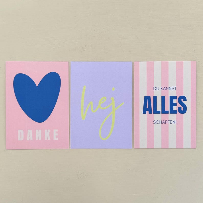 May include: Three square cards with text and designs. The first card is pink with a blue heart and the word "DANKE". The second card is lavender with the word "hej" in yellow. The third card is striped pink and white with German text.
