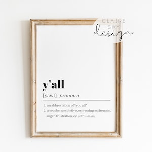 May include: A framed print with a definition of the word "y'all" in a simple black font. The definition states that "y'all" is an abbreviation of "you all" and a southern expletive expressing excitement, anger, frustration, or enthusiasm.