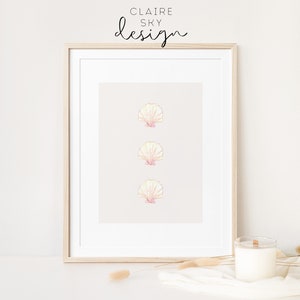 May include: A framed print with three pink and yellow seashells on a light beige background. The frame is light wood and the text 'CLAIRE SKY design' is at the top of the print.