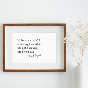 May include: A framed print with a quote about life starting again in the fall. The quote reads "life starts all over again when it gets crisp in the fall." The quote is attributed to F. Scott Fitzgerald.