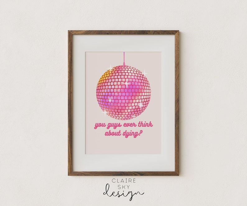 Puede incluir: Impresi&oacute;n art&iacute;stica enmarcada con una bola de discoteca rosa y magenta y el texto "you guys ever think about dying?". La obra de arte est&aacute; sobre un fondo rosa claro y enmarcada en un marco de madera marr&oacute;n.