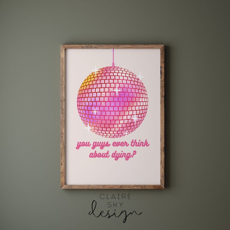 Puede incluir: Un estampado enmarcado con una bola de discoteca rosa y amarilla y el texto "you guys ever think about dying?" en rosa. El estampado es de Claire Sky Design y tiene un marco de madera.