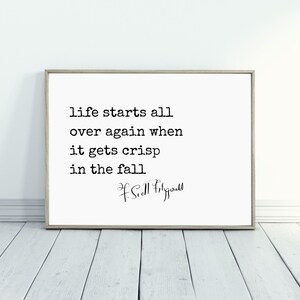 May include: A black and white typography print with the quote "Life starts all over again when it gets crisp in the fall" by F. Scott Fitzgerald.