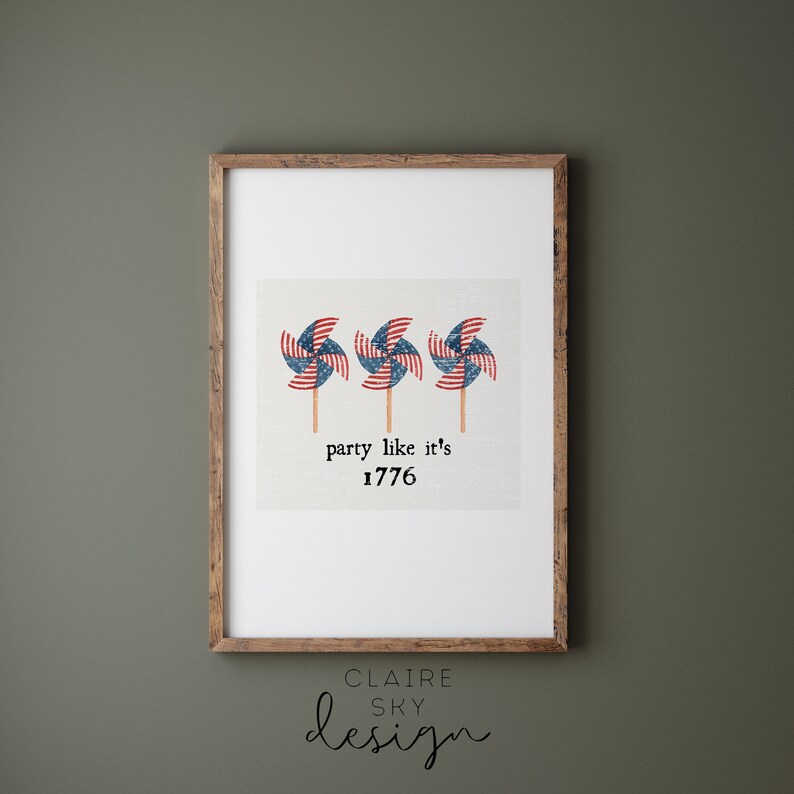 Op de afbeelding: Een ingelijste print met drie windmolens met het ontwerp van de Amerikaanse vlag. De tekst "party like it's 1776" staat onder de windmolens.