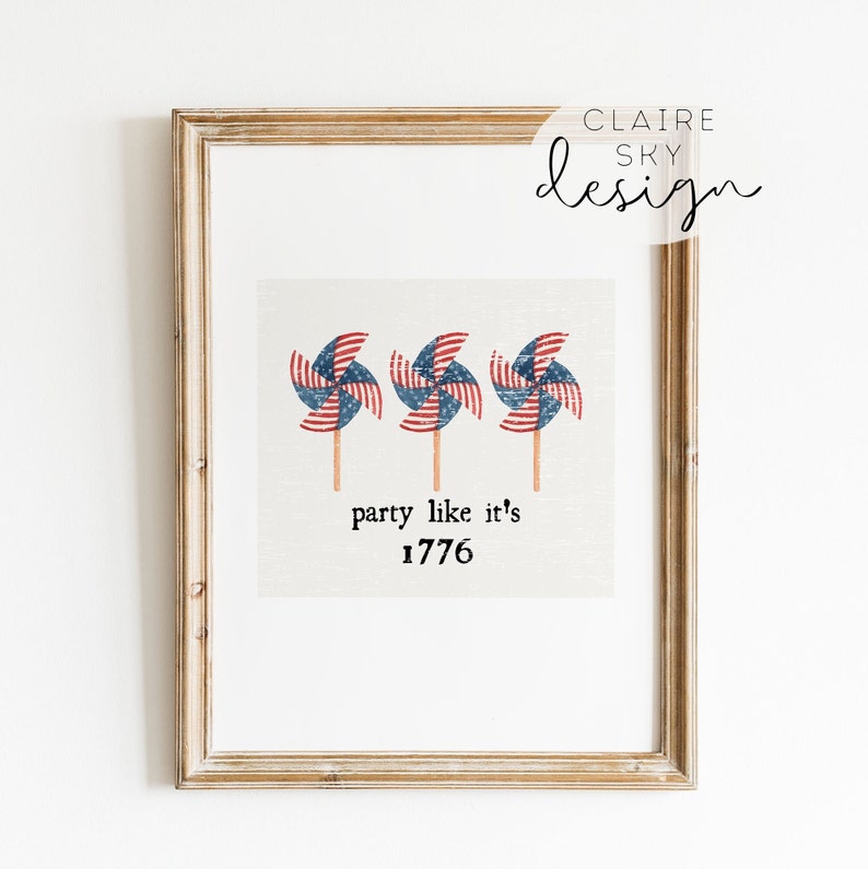 Op de afbeelding: Een ingelijst afdruk met drie rood, wit en blauwe windmolens met de tekst "party like it's 1776".