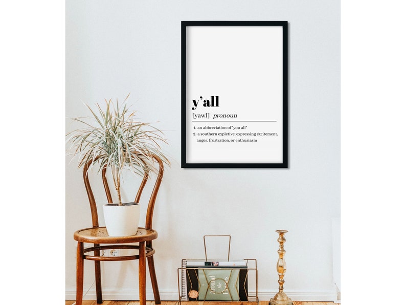 May include: A black framed print with a white background and the word "y'all" in bold black text. The definition of the word is written in smaller black text below. The definition is: "[yawl] pronoun 1. an abbreviation of 'you all' 2. a southern expletive, expressing excitement, anger, frustration, or enthusiasm"