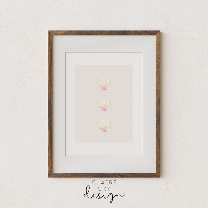 May include: A framed print with three pink and yellow seashells in a vertical line on a light pink background. The frame is brown wood. The text at the bottom of the print reads 'CLAIRE SKY design'.