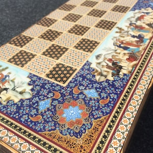 以下が含まれることがあります： カラフルで複雑なデザインのウッドチェスボード。ボードは、黒と白の正方形の伝統的なチェスボードパターンを特徴とし、花柄と幾何学模様のボーダーで囲まれています。ボードは、風景の中に人々や動物のシーンで飾られています。