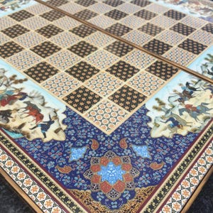 Puede incluir: Un tablero de ajedrez plegable con una cuadrícula central de cuadrados alternos de color marrón oscuro y beige claro con patrones geométricos complejos. El borde muestra ilustraciones detalladas de jinetes y motivos florales en azul, rojo y oro.