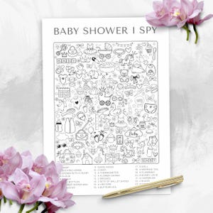 May include: A black and white "Baby Shower I Spy" game sheet with baby-themed illustrations. The sheet includes a rocking horse, dresses, and a unicorn. A gold pen and pink flowers are also in the image.