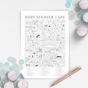 May include: A black and white "Baby Shower I Spy" game sheet with a list of items to find. The sheet includes illustrations of baby-related objects like a rattle, bottles, and onesies. A rose gold pen and confetti are in the image.